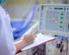 nurse with clipboard checking dialysis machine