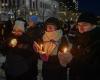 People outdoors on a snowy night wearing warm clothes and holding glowing candles