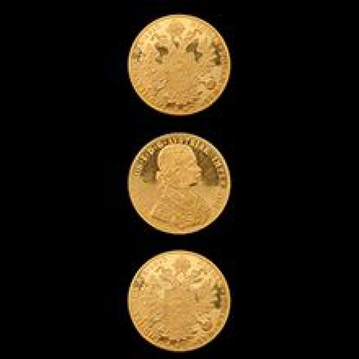 three gold coins against a black background