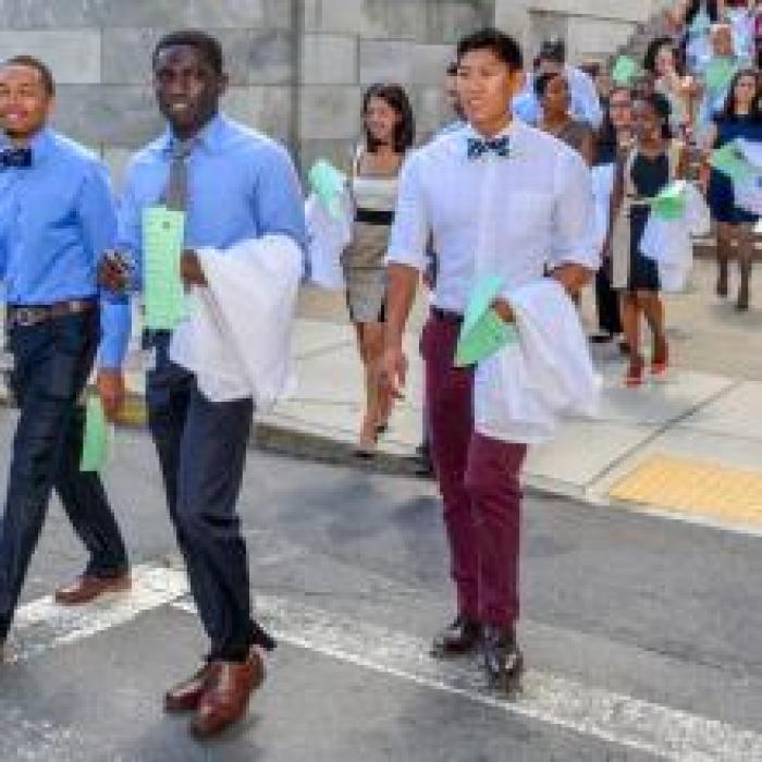two male medical students crossing a street carrying their white coats over their arms