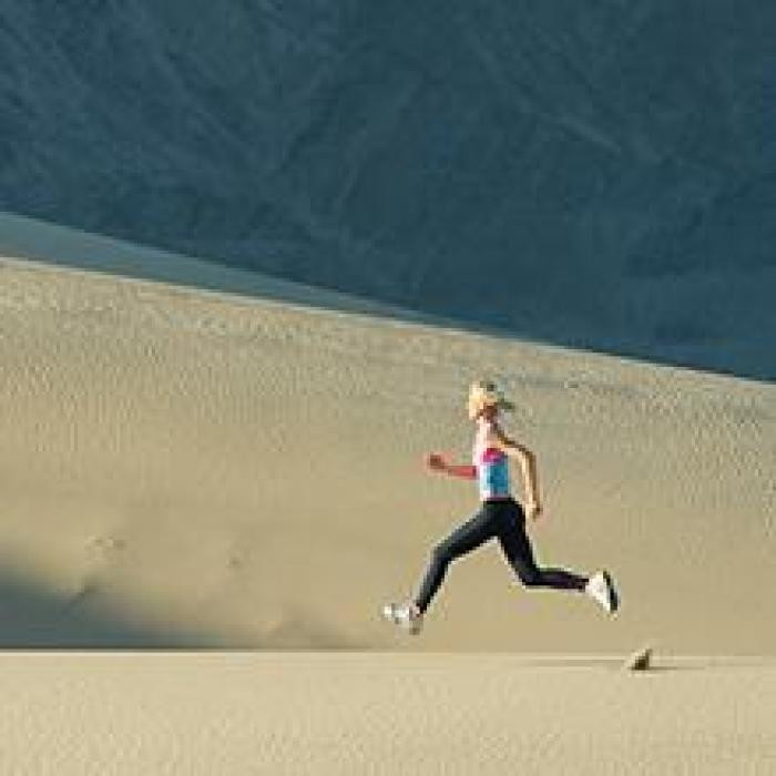 woman running along sand dunes