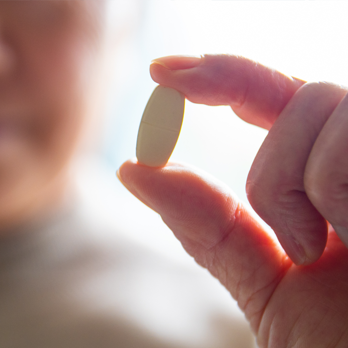 fingers holding oblong pill