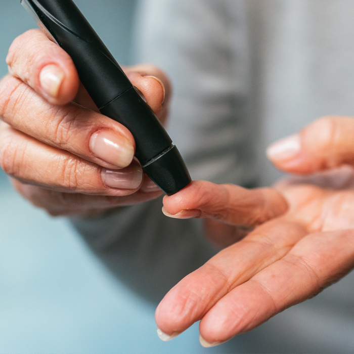 close up of a person puncturing their finger for a diabetes check