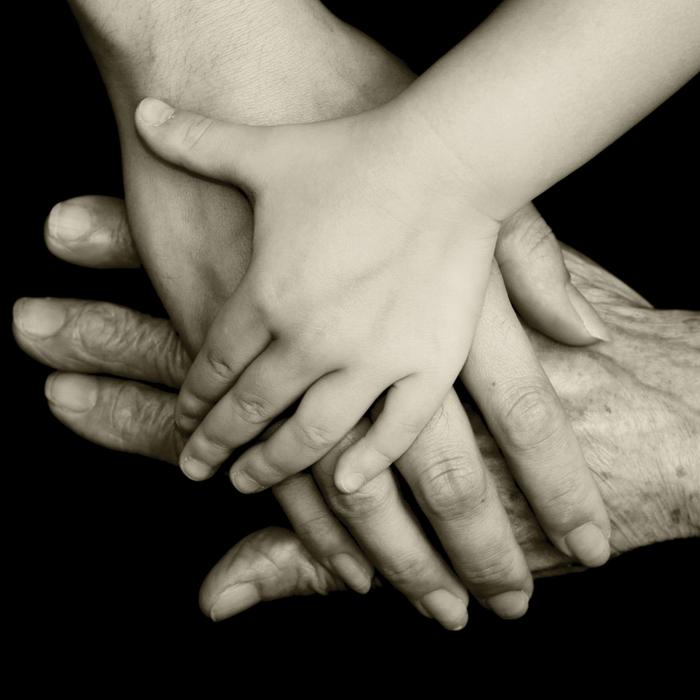 hands of three different people, three different ages, crossed