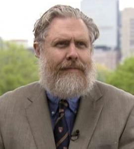 Head shot of Church in a suit with trees in the background