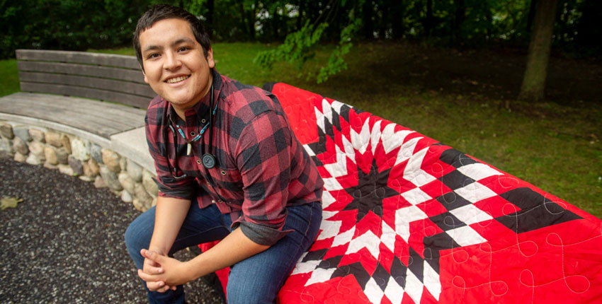 Photo of Lopez-Carmen sitting on a stone wall