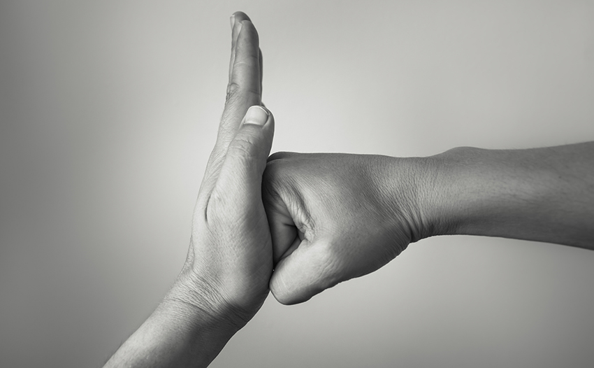 Black and white photograph of one hand stopping another hand from punching