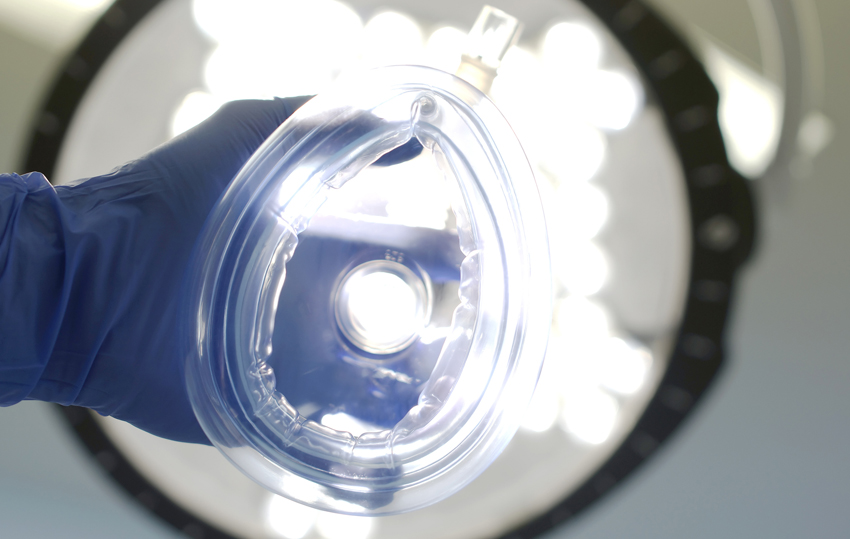 anesthetic mask held toward camera as if being put on the viewer