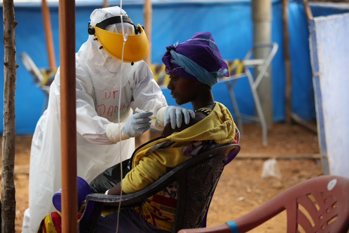 Image of person in full protective gear examining a patient