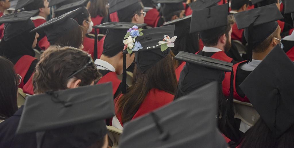 Graduating students wearing mortarboard caps, including one decorated with flowers.