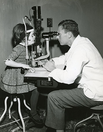 A black-and-white photo of Claes Dohlman with a pediatric patient